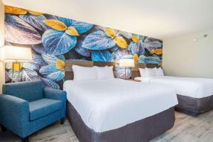 una habitación de hotel con 2 camas y una silla azul en Clarion Pointe South Boston - Danville East, en South Boston