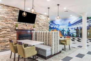 a dining room with a fireplace and a tv on a brick wall at Clarion Pointe South Boston - Danville East in South Boston