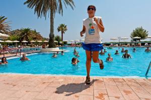 a woman running in front of a swimming pool at Cathrin Hotel in Faliraki