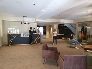 un hall avec des personnes assises à un comptoir dans un bâtiment dans l'établissement Garden & City Cauterets Balneo, à Cauterets