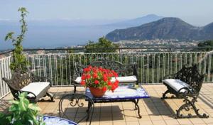 een patio met stoelen en een tafel met een pot bloemen bij Villa Cinzia in Sant'Agnello