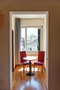 ein Esszimmer mit einem Tisch, 2 Stühlen und einem Fenster in der Unterkunft Al Giardinetto in Biasca