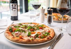 una pizza en un plato en una mesa con copas de vino en Al Giardinetto, en Biasca