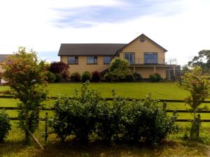 a house in a field with a fence at La Mirage B&B in Bantry