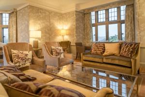 a living room with chairs and a couch and windows at Cragwood Country House Hotel in Windermere