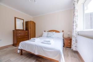 a bedroom with a white bed with a mirror and a window at Sea Dream House Kessingland Air Manage Suffolk in Lowestoft