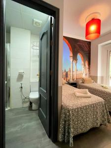a bedroom with two beds and a bathroom at Hostal Paco´s in Seville