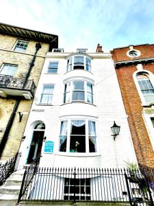 a white building with a fence in front of it at Bayliss Hall Guesthouse in Weymouth