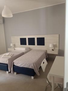 een witte slaapkamer met 2 bedden en een bureau bij La Lume in Partanna