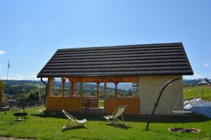 een klein huis met een prieel en stoelen bij Osada Witów - apartament „Siwa Kopa” in Witów