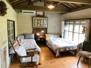 a bedroom with two beds and a desk and a window at Travelers House おーさんてぃん青空舎 in Taketomi