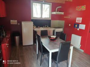 kuchnia z czerwonymi ścianami oraz stołem i krzesłami w obiekcie Appartement Saint Bauzély w mieście Saint-Bauzély