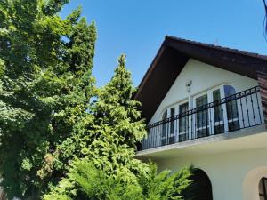 Casa con balcón y árboles en Kossuth Apartman en Hajdúszoboszló