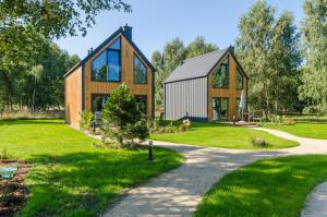 a large wooden house with glass windows on a lawn at Domki w Naturze in Lubiatowo