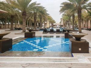 a swimming pool with palm trees in a resort at Royal Club By RVHR, Grandeur Residence Crescent Palm Jumeirah in Dubai