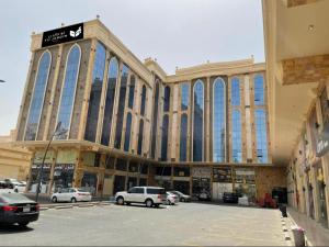 ein großes Gebäude mit Autos auf einem Parkplatz in der Unterkunft Tu Jardin Al Marwa- توجاردن المروه in Dschidda