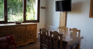 een eetkamer met een tafel, stoelen en een televisie bij travelski home select - Résidence Boedette in Les Menuires