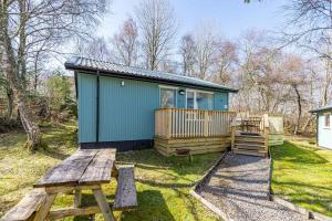 a small green cabin with a picnic table and a bench at Bracken Lodge 8 with Hot Tub in Belladrum