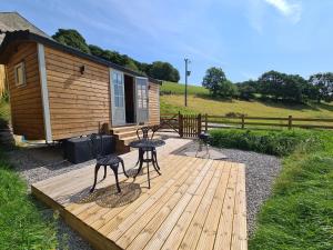a wooden deck with a table and chairs in front of a cabin at Peak District Shepherds Hut in Hope