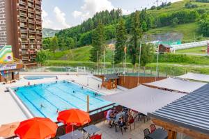 a large swimming pool with people sitting around it at Studio 4pers vue piste in Le Corbier