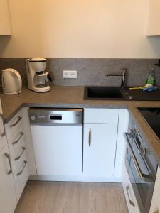a kitchen with white cabinets and a sink at Dünenbake, App 62, Helgolandblick in Sankt Peter-Ording +3 photos
