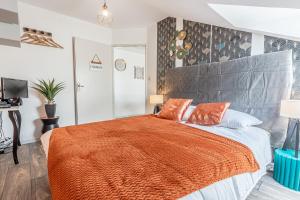 ein Schlafzimmer mit einem großen Bett mit einer orangefarbenen Decke in der Unterkunft L'abstrait Metz Thionville Wifi Un-Séjour-à-Part in Mondelange