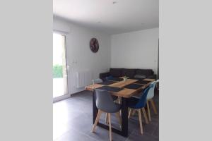 a dining room with a wooden table and blue chairs at Maison Lulalilo in Crémeaux