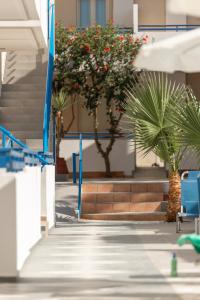 un edificio con palmeras, sillas azules y escaleras en Marie Κelly Apartments, en Gouves