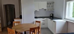 a kitchen with white cabinets and a wooden table at Apartamenty EverySky - Konstytucji 3 go Maja 66-2 in Karpacz