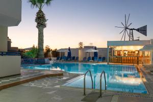 a pool with a palm tree and a windmill at Marie Κelly Apartments in Gouves