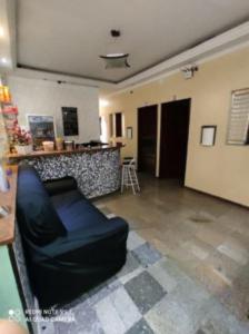 a living room with a black couch in a room at Hotel Vila Maria in Sao Paulo