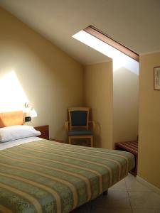 1 dormitorio con 1 cama, 1 silla y 1 ventana en Cerruti Hotel, en Vercelli