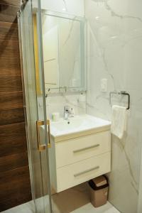 a white bathroom with a sink and a mirror at Apartmani President I in Banja Luka +26 photos