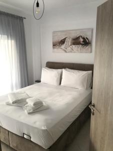 - une chambre avec un lit blanc et une horloge murale dans l'établissement Cyclops Luxury Apartments, à Igoumenítsa