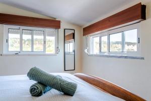 a bedroom with two windows and a bed at Natural Mystic Hostel in Costa da Caparica
