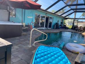 a swimming pool with an umbrella and an inflatable at This Homestay Oasis Is The Cape's Best Place To Stay in Cape Coral