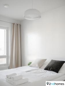 a white bedroom with a white bed and a window at 2ndhomes Tampere "Pyynikinkulma" Apartment - SAUNA & Amazing Views in Tampere