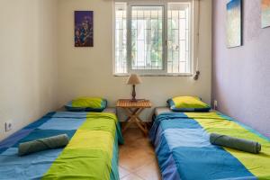 two beds in a room with a table and a window at Natural Mystic Hostel in Costa da Caparica