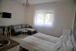 1 dormitorio con cama, sofá y lavamanos en River Apartment, en Makó