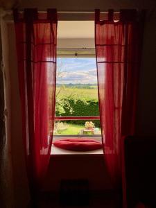 a window with red curtains in a room with a view at Chambre des Anges & Roulotte proche Mont Saint-Michel, l'Angevinière in Saint-Laurent-de-Terregatte