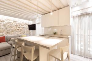 a kitchen with white cabinets and a table and chairs at Spianada Collection of Studios & Apartments by Konnect in Corfu