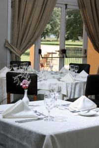 a group of tables with white table cloths and wine glasses at Hotel Colonial San Nicolás in San Nicolás de los Arroyos