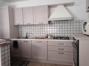 a white kitchen with white cabinets and a sink at Casa vacanze Bau Mela in Villanova Strisaili