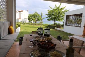 a table with food and wine glasses on a patio at Anemi Beach, Seafront in Nea Skioni