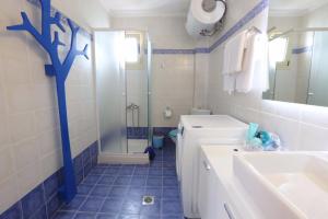 a blue and white bathroom with a sink and a shower at Anemi Beach, Seafront in Nea Skioni +17 photos