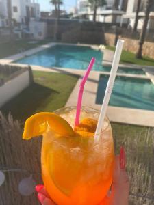 una persona che tiene un bicchiere di succo d'arancia accanto alla piscina di Casa Mordi a Villamartin