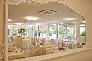 a dining room with white tables and chairs and a mirror at Hotel Euromar in Marina di Massa