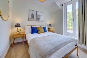 una camera da letto con un letto con cuscini blu e una finestra di Church Bells House by Spa Town Property - 3 Bedroom Georgian Townhouse in Central Warwick a Warwick