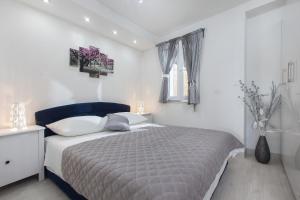 ein weißes Schlafzimmer mit einem Bett und einem Fenster in der Unterkunft Apartments Orka in Promajna