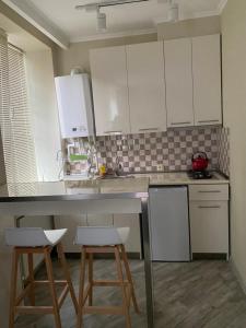 a kitchen with white cabinets and two stools at nikani1 in Borjomi
